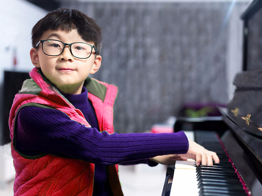 Boy happily plays the piano